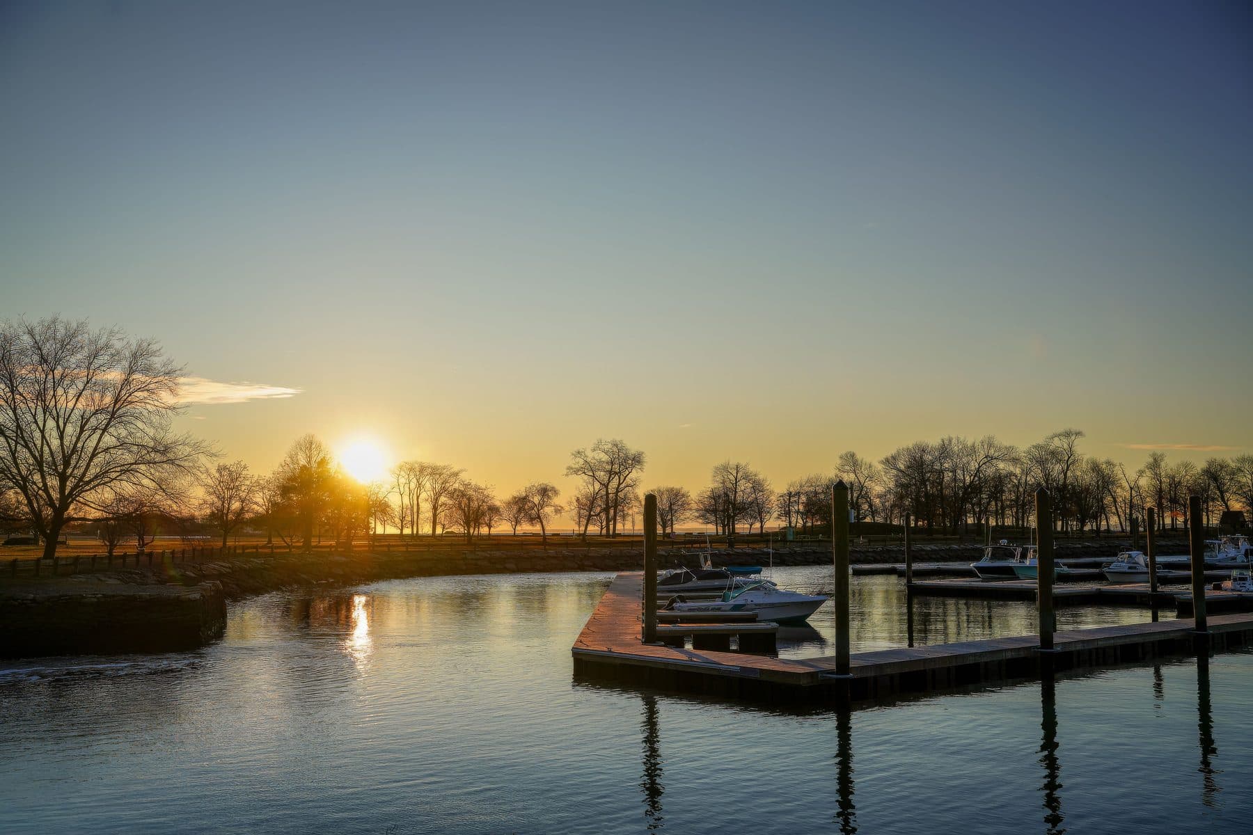 A marina dock at sunset with boats moored along the water