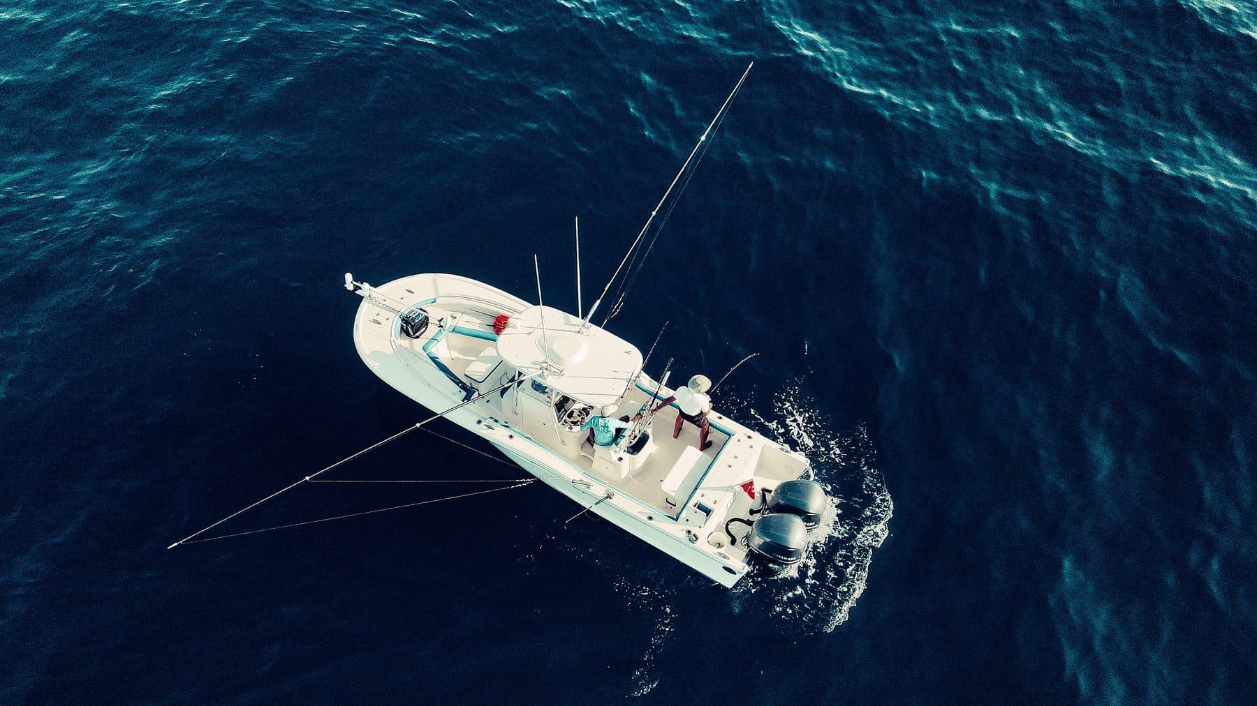 Aerial view of a center-console fishing boat trolling open ocean water