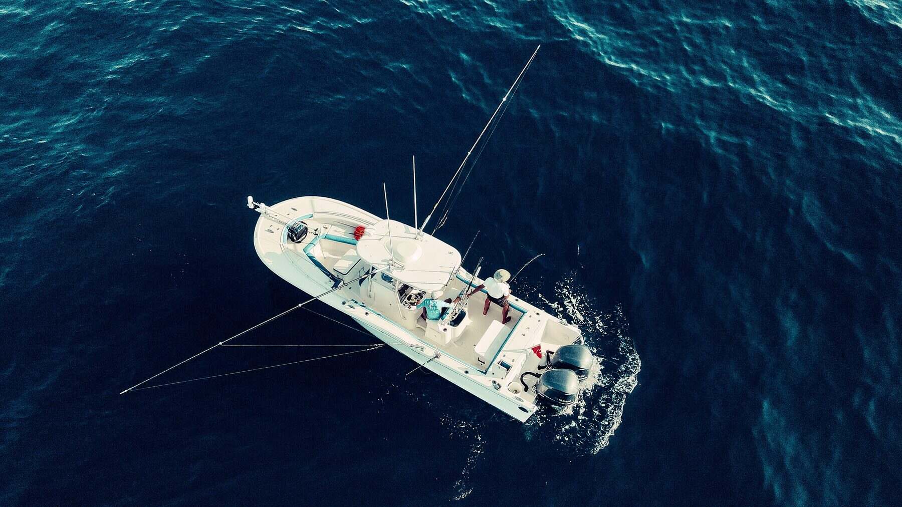 Aerial view of a center-console fishing boat trolling open ocean water